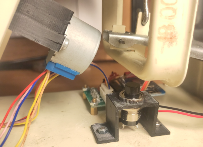 The motor and button mounted with brackets, and electronics in background. Red and black wire is going to a barrel plug in back of the scale for power.
